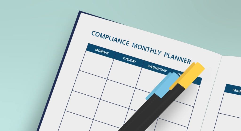 Illustration of a compliance monthly planner with two pens laying across it