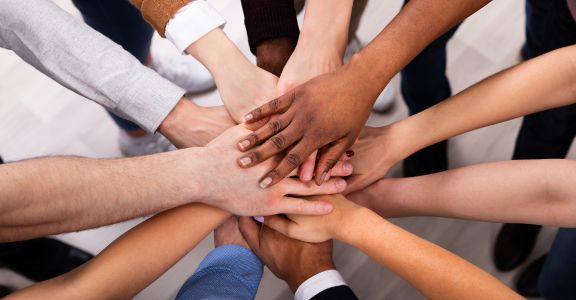 Diverse group of people doing an all hands in