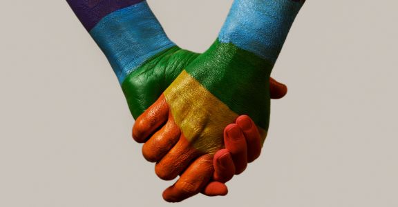 lgbtqia+ image of two people holding hands with rainbow stripes