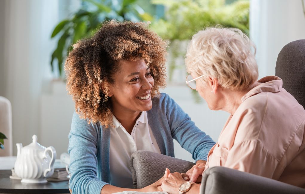 Caregiver sitting with elderly woman at home