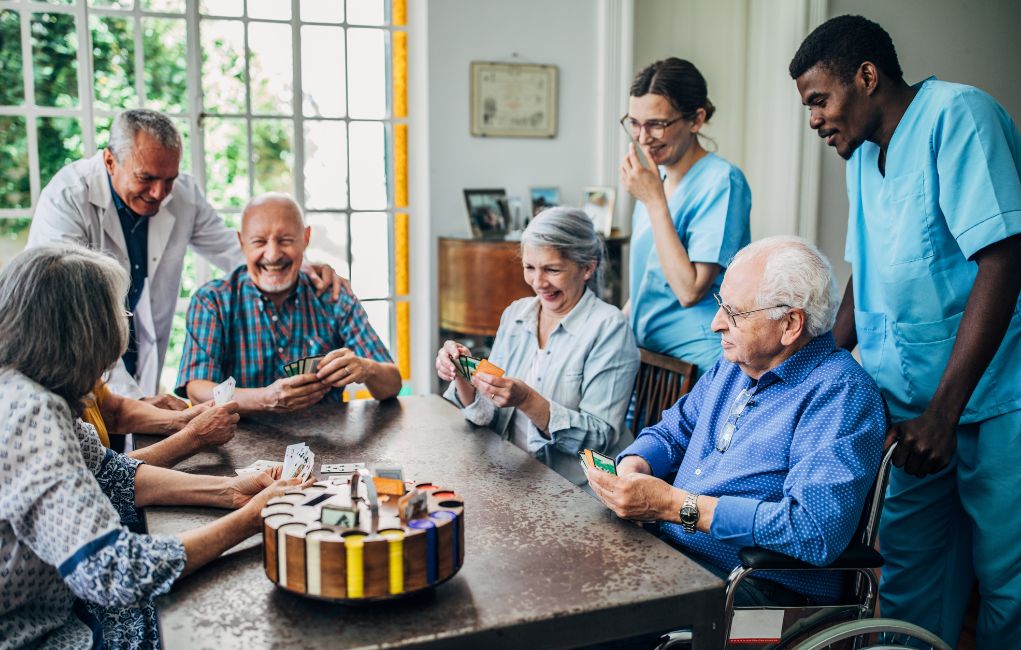 Aides watching assisted living residents play cards