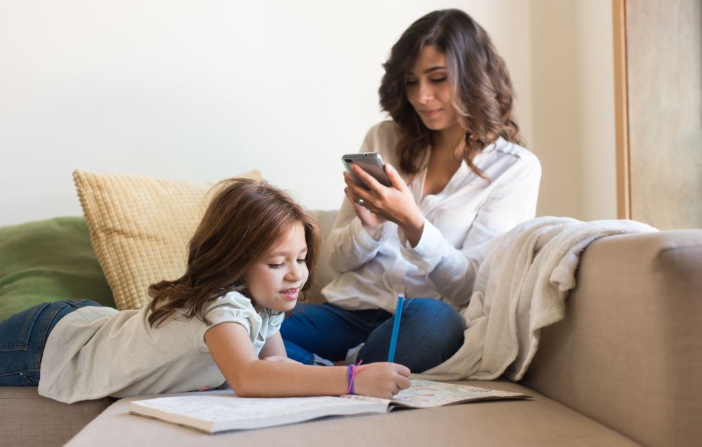 woman completing an in-service training course from her home while her child draws