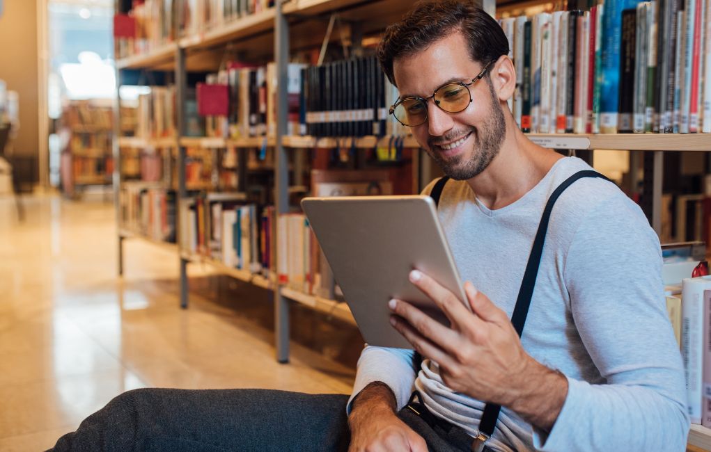 man looking at tablet in a library